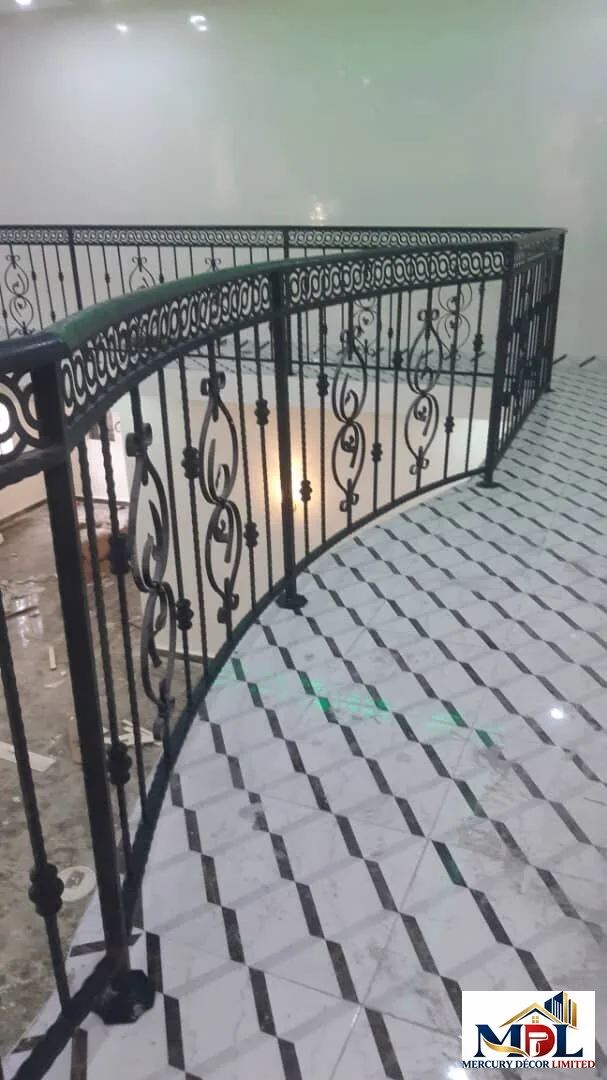A decorative stainless and gold balcony railing overlooking a patterned floor.
