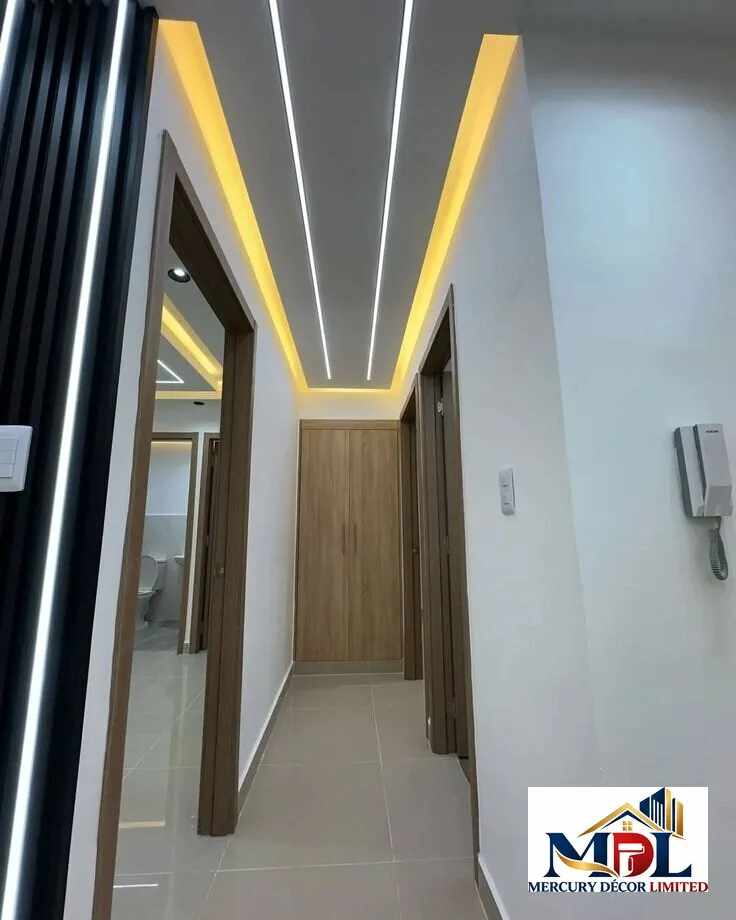 A layered ceiling with black trims, warm lighting and a geometric centrepiece.